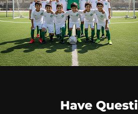 A youth team lined up with their coach in front of the Dubai skyline
